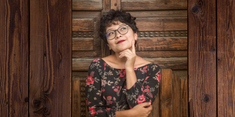 Woman leaning up against a wooden wall thinking